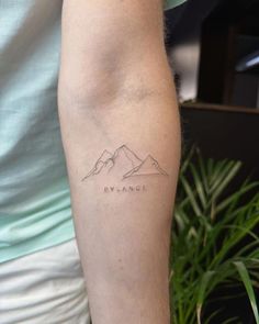 a man with a tattoo on his arm that says, avalanche in the mountains behind him