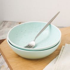 two bowls with forks in them sitting on a cutting board