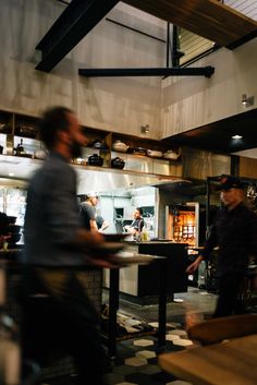 two men working in a restaurant kitchen with black and white checkered flooring on the walls