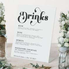 a menu with flowers and greenery is displayed in front of two vases on the table