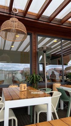 an outdoor dining area with wooden tables and wicker lamps hanging from the rafters