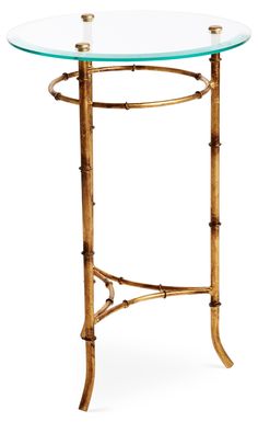 a glass table with gold bamboo legs and an oval glass tabletop on the top