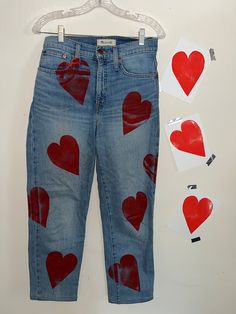 a pair of blue jeans with red hearts painted on them next to some cut outs