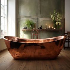 a large copper bath tub sitting on top of a wooden floor next to a window