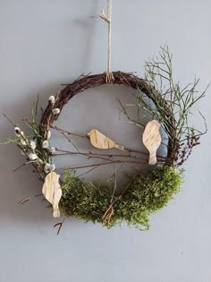 a wreath hanging on the wall with three wooden spoons and some plants in it