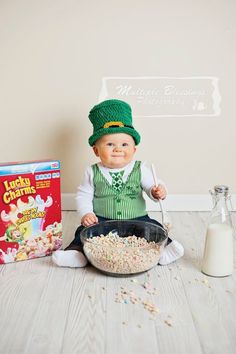 a baby sitting on the floor with cereal and milk