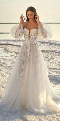 a woman in a wedding dress standing on the beach