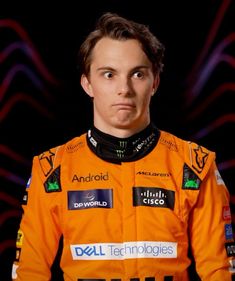 a close up of a person wearing an orange racing suit and looking at the camera