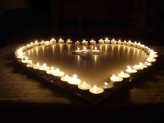 many lit candles are arranged in the shape of a heart