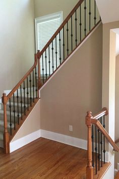 an empty room with stairs and hard wood flooring on the wooden floors in front of a window