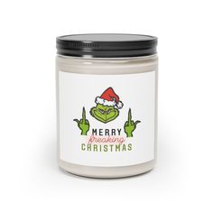 a christmas candle with the grin face on it and merry greetings written in green