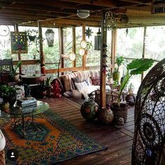 a living room filled with lots of furniture and plants on top of a wooden floor