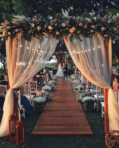 an outdoor wedding setup with white flowers and sheer draping over the ceremony aisle