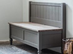 a bed with a wooden headboard and foot board next to a basket on the floor