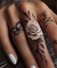 two fingers with tattoos on them, one has a rose and the other has butterflies