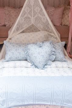 a bed with a canopy over it and pillows on the bottom half, along with two bedspreads