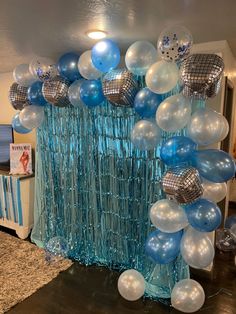 balloons and streamers are hanging from the ceiling in front of a blue curtain with disco balls on it