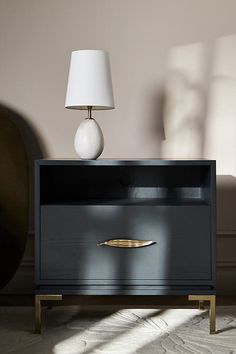 a black and gold nightstand with a white lamp on top