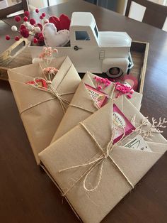 two wrapped gifts sitting on top of a wooden table next to a white toy truck