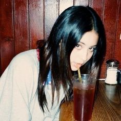 a woman drinking from a tall glass with a straw in her mouth