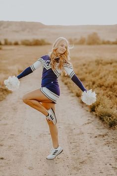 a woman in cheerleader gear dancing on a dirt road