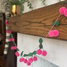 pink pom - poms hanging from a mantle