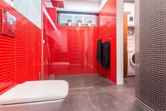 a red tiled bathroom with a white toilet