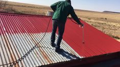 a man is standing on top of a metal roof with a dog tied to it