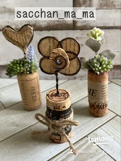 three wine corks with flowers in them on a wooden table next to a sign that says sachan ma ma