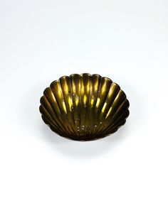 a gold shell shaped bowl sitting on top of a white table