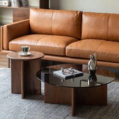 a brown leather couch sitting next to a glass table on top of a carpeted floor