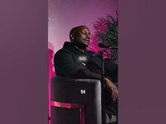 a man sitting in a chair next to a plant