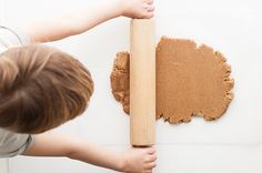 a young boy is playing with a wooden block and some brown paint on the wall