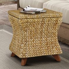 a wicker stool with magazine on it in front of a couch and coffee table