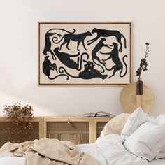 a bed with white sheets and pillows in front of a framed artwork on the wall