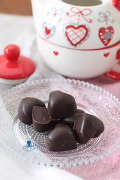 chocolate hearts on a glass plate next to a tea pot