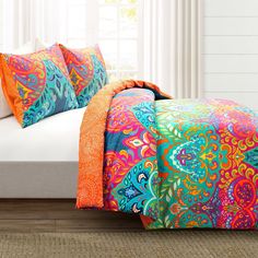 a bed with colorful pillows on top of it and a white headboard in the background