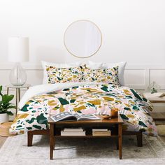 a bedroom with white walls and floral comforter covers on the bed, along with a round mirror