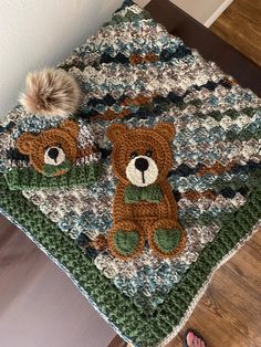 a crocheted teddy bear blanket on top of a wooden floor next to a person's feet