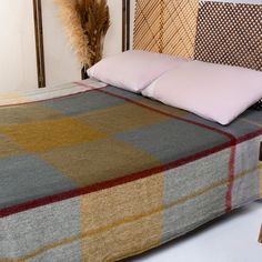 a bed with a checkered blanket and pillows on it, next to a wooden headboard