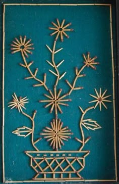 an intricately designed wall hanging with flowers and leaves on blue background, in the shape of a basket