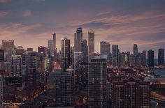 the city skyline is lit up at night, with skyscrapers in the foreground