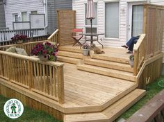 a person sitting on a wooden deck in front of a house