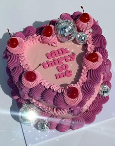 a heart shaped cake with pink frosting and cherries