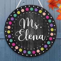 a wooden sign hanging on the side of a blue door that says,'mrs ellena '