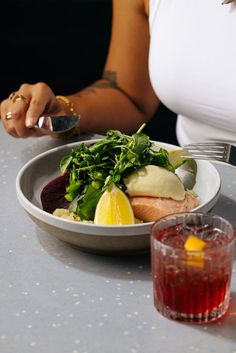 a woman sitting at a table with a plate of food and drink in front of her