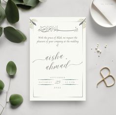 the wedding card is on top of a table with some greenery and other items