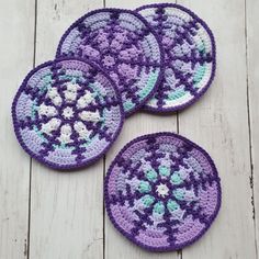 four crocheted coasters sitting on top of a wooden table