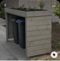 an outdoor planter with two trash cans and plants in the top part of it