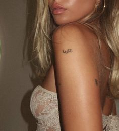 a close up of a person with a tattoo on her arm and shoulder, wearing a white dress